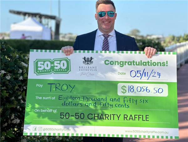 Troy holds his raffle prize cheque